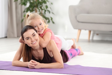 Photo of Woman with daughter lying on fitness mat at home. Space for text