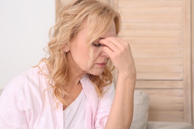 Woman suffering from headache on sofa at home. Hormonal disorders