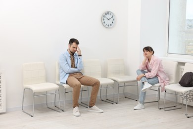 Man and woman waiting for appointment indoors