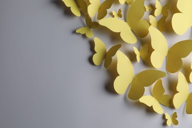 Photo of Yellow paper butterflies on light grey background, top view. Space for text