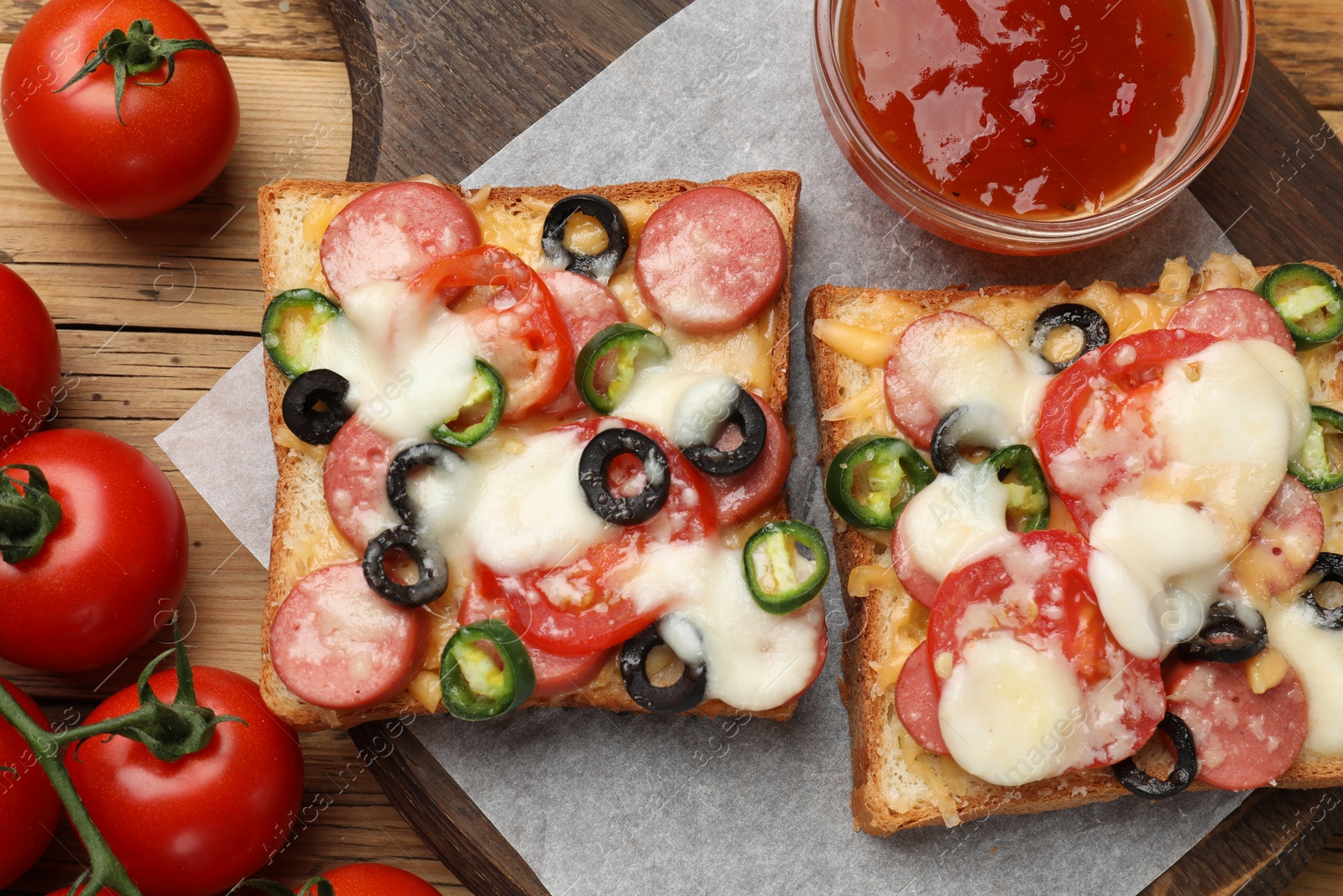 Photo of Tasty pizza toasts, sauce and tomatoes on wooden table, flat lay