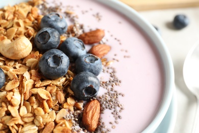 Photo of Bowl of tasty oatmeal with blueberries and yogurt on table, closeup