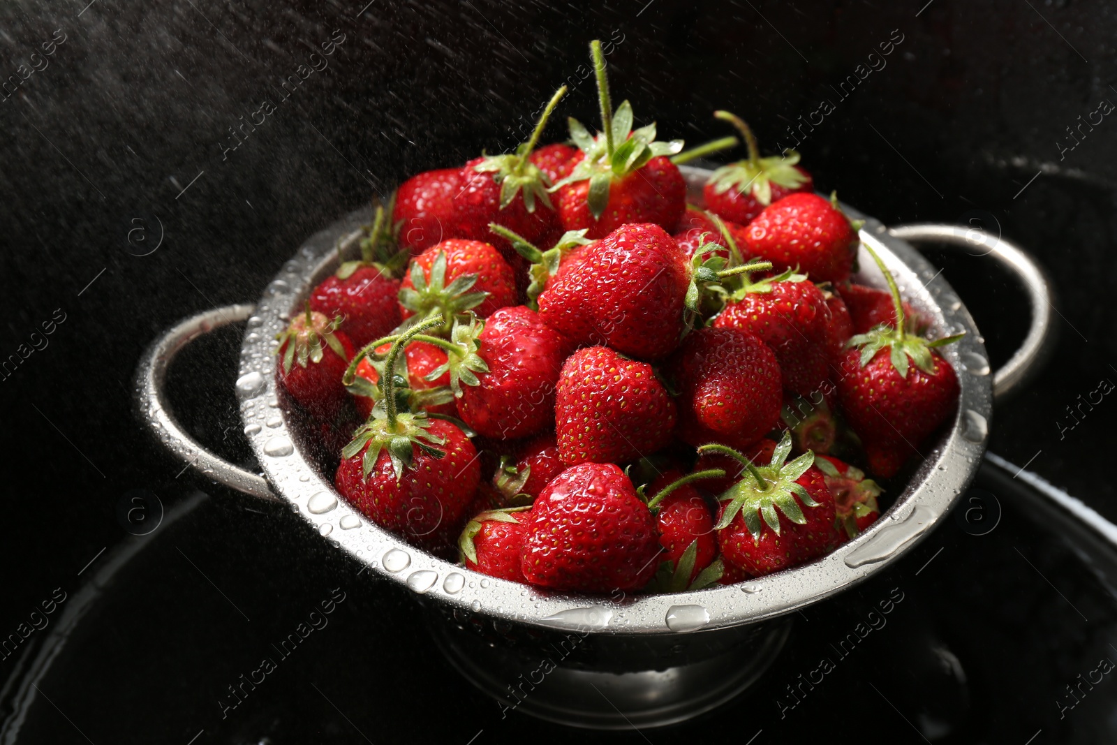 Photo of Metal colander with fresh wet strawberries in sink