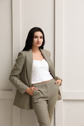 Photo of Beautiful woman in formal suit near light grey wall. Business attire