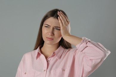Photo of Young woman suffering from migraine on grey background