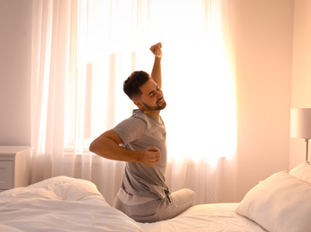 Young man stretching on bed at home. Lazy morning