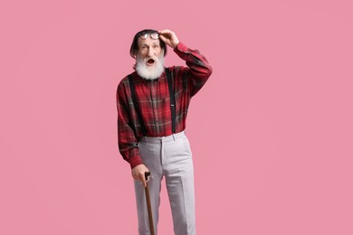 Photo of Surprised senior man with walking cane on pink background