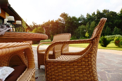 Photo of Rattan armchairs and table at backyard near beautiful garden