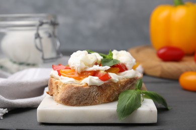 Photo of Delicious sandwich with burrata cheese and tomatoes on grey wooden table, closeup