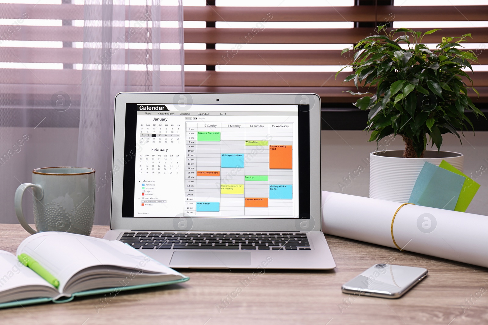 Photo of Laptop with calendar on wooden table in office