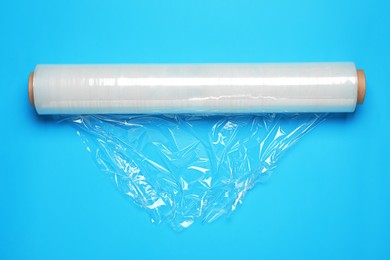 Photo of Roll of transparent stretch wrap on turquoise background, top view