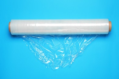 Roll of transparent stretch wrap on turquoise background, top view