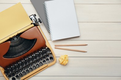 Vintage typewriter, stationery and crumpled paper on white wooden table, flat lay. Space for text