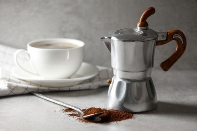 Ground coffee, moka pot and cup with drink on light grey table