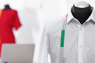 Photo of Mannequin with shirt and measuring tape in tailor studio, closeup