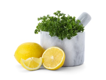 Photo of Mortar with green fresh parsley and lemons on white background