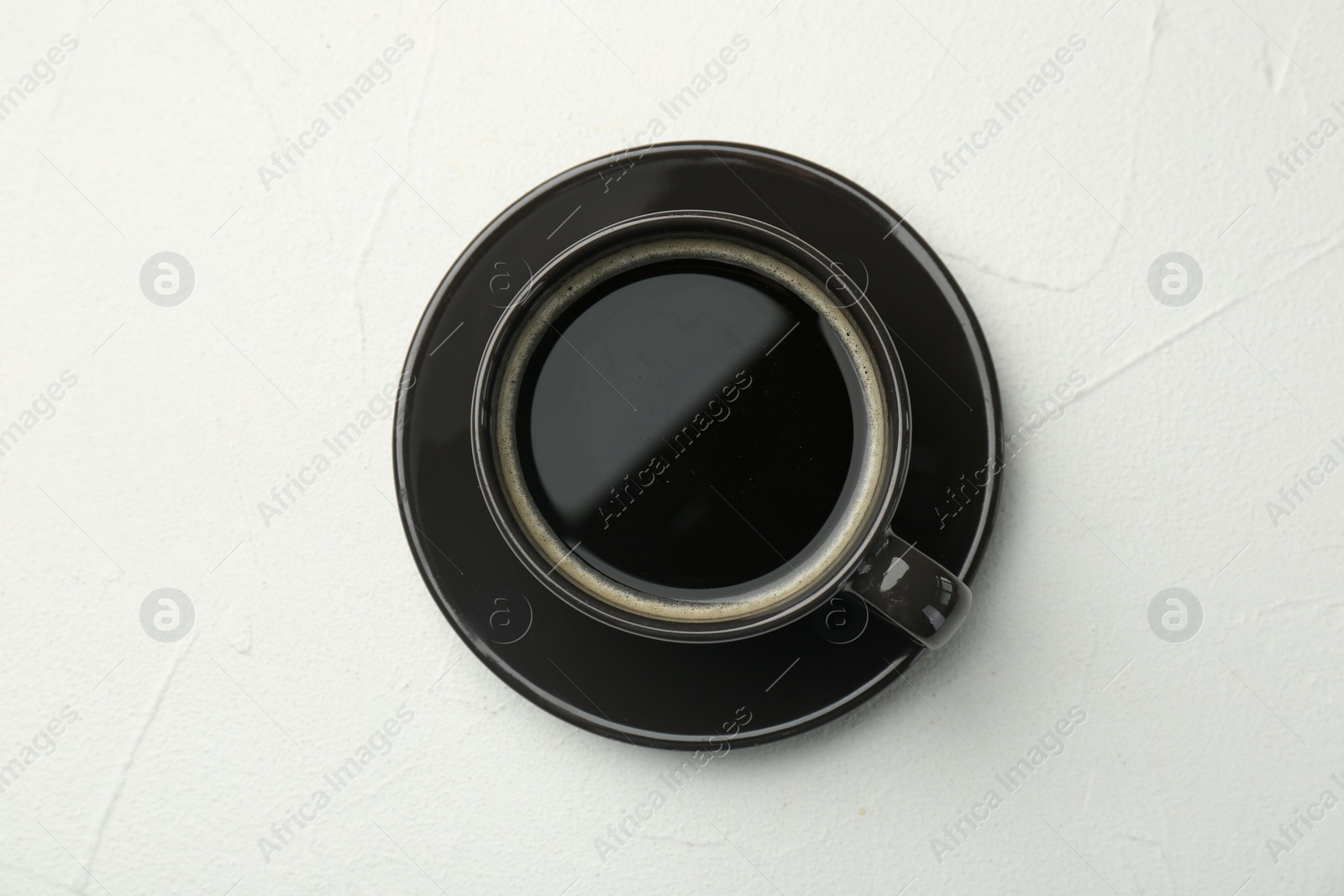 Photo of Hot coffee in cup on white textured table, top view