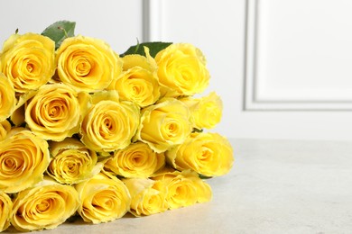 Photo of Beautiful bouquet of yellow roses on light grey table, closeup. Space for text