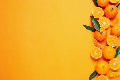 Photo of Flat lay composition with fresh ripe tangerines and space for text on orange background. Citrus fruit