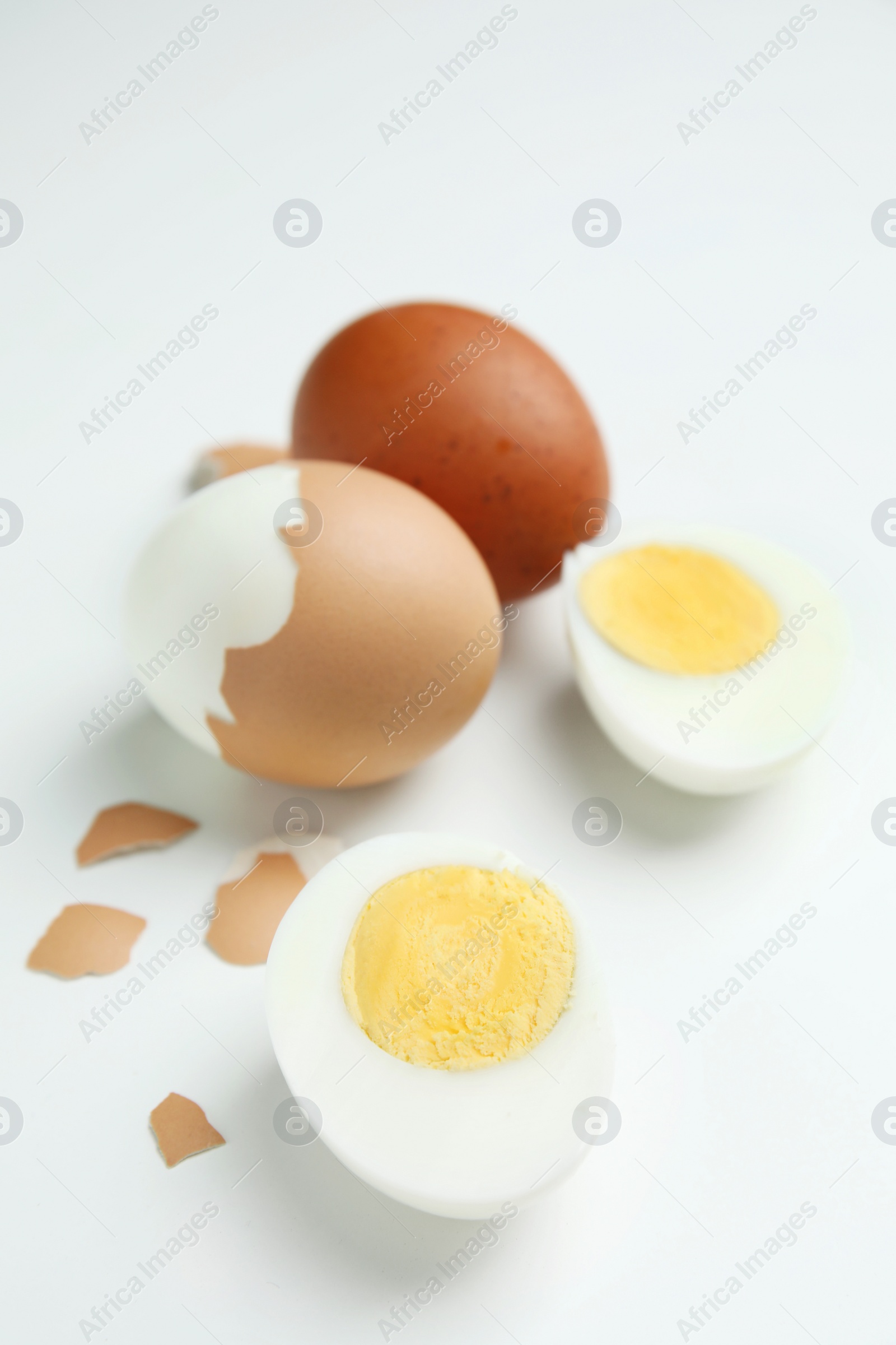 Photo of Hard boiled eggs and pieces of shell on white background