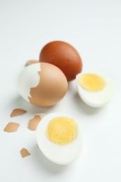 Hard boiled eggs and pieces of shell on white background