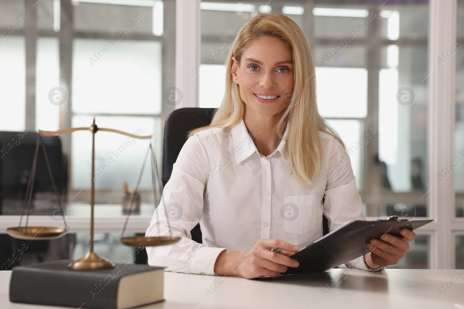 Photo of Portrait of smiling lawyer with clipboard at workplace in office