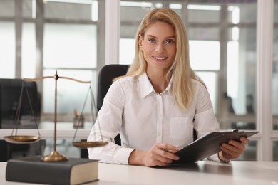 Photo of Portrait of smiling lawyer with clipboard at workplace in office