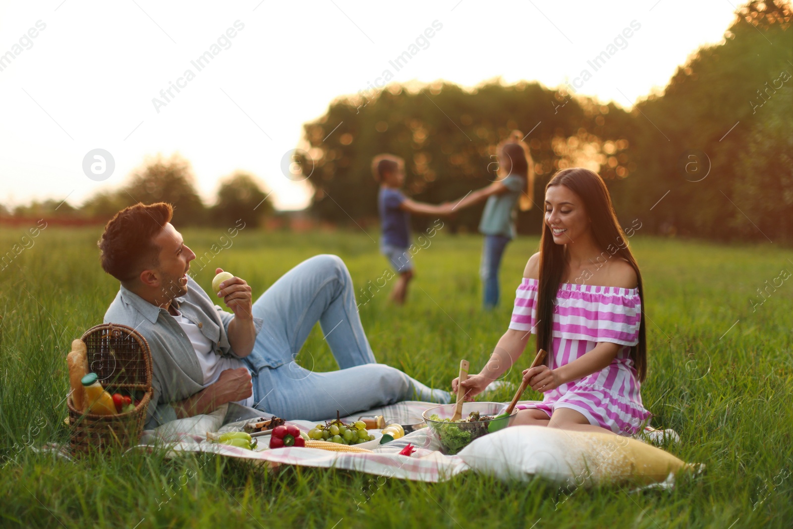 Photo of Happy family having picnic in park at sunset