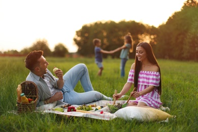 Photo of Happy family having picnic in park at sunset