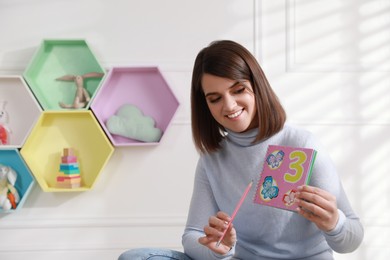 Photo of Happy female English teacher giving lesson indoors. Early childhood education