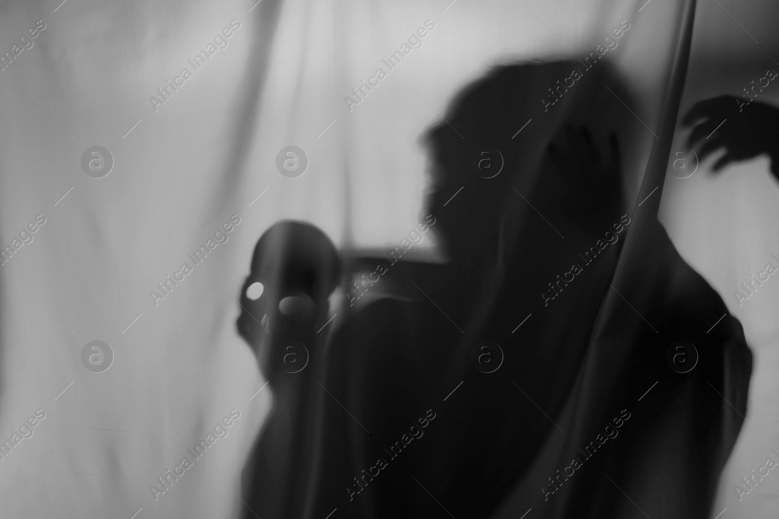 Photo of Silhouette of creepy ghost with skull behind grey cloth, space for text