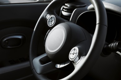 Black steering wheel inside of modern car, closeup