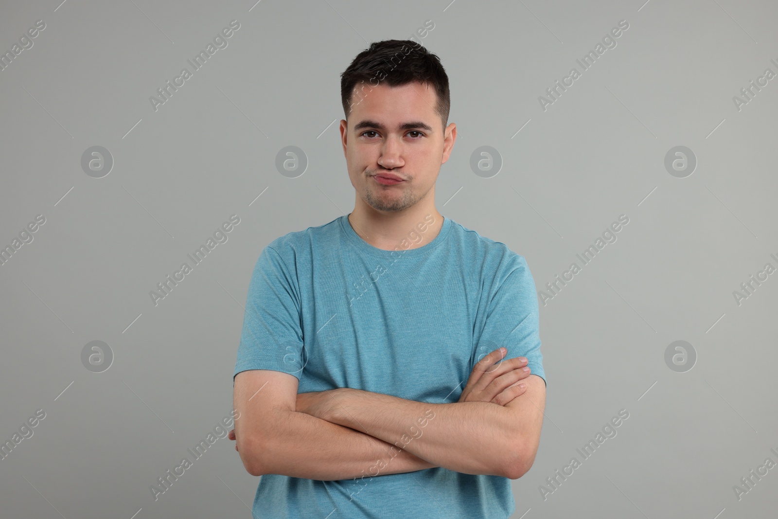 Photo of Resentful man with crossed arms on grey background