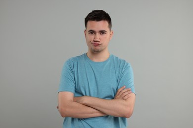 Resentful man with crossed arms on grey background