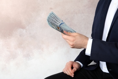 Photo of Businessman in suit holding money on color background. Space for text