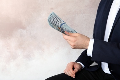 Businessman in suit holding money on color background. Space for text