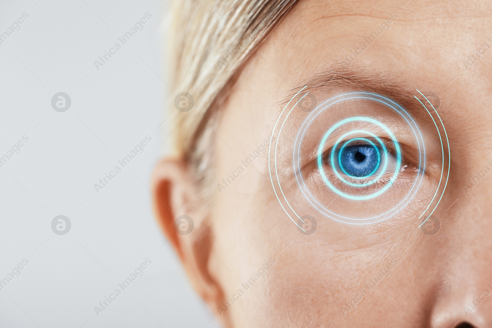 Image of Vision test. Mature woman and digital scheme focused on her eye against white background, closeup
