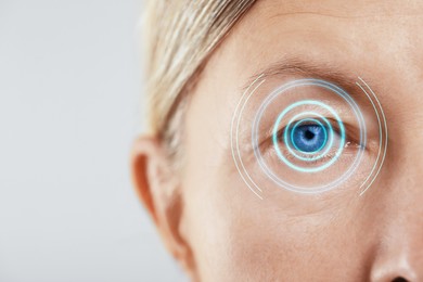 Image of Vision test. Mature woman and digital scheme focused on her eye against white background, closeup