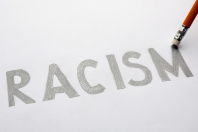 Photo of Erasing word Racism written on paper sheet with pencil, closeup