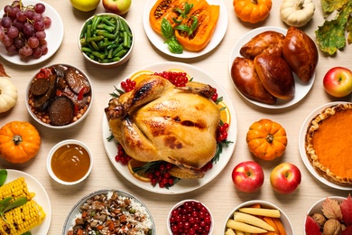 Photo of Traditional Thanksgiving day feast with delicious cooked turkey and other seasonal dishes served on wooden table, flat lay