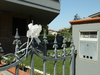 Photo of Metal fence with white bow on sunny day