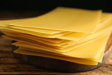 Photo of Uncooked lasagna sheets on wooden table, closeup
