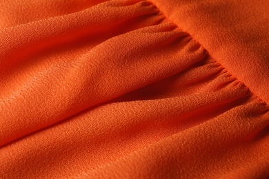 Photo of Texture of orange fabric with folds as background, closeup