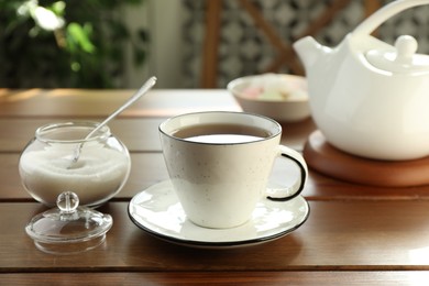 Photo of Cup of aromatic tea and sugar on wooden table