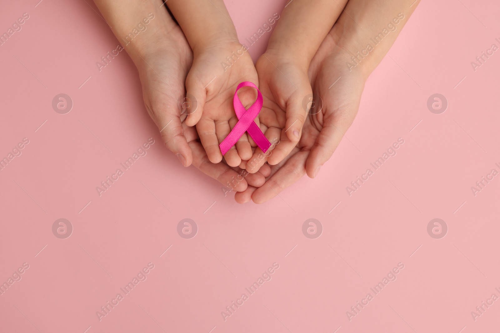 Photo of Woman and child holding pink ribbon on color background, top view with space for text. Breast cancer awareness