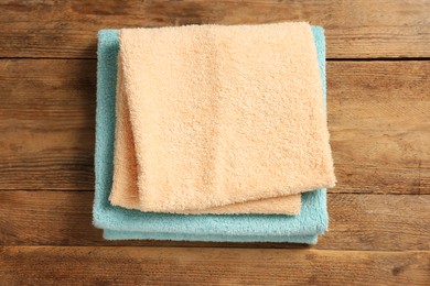 Photo of Soft folded colorful terry towels on wooden table, top view