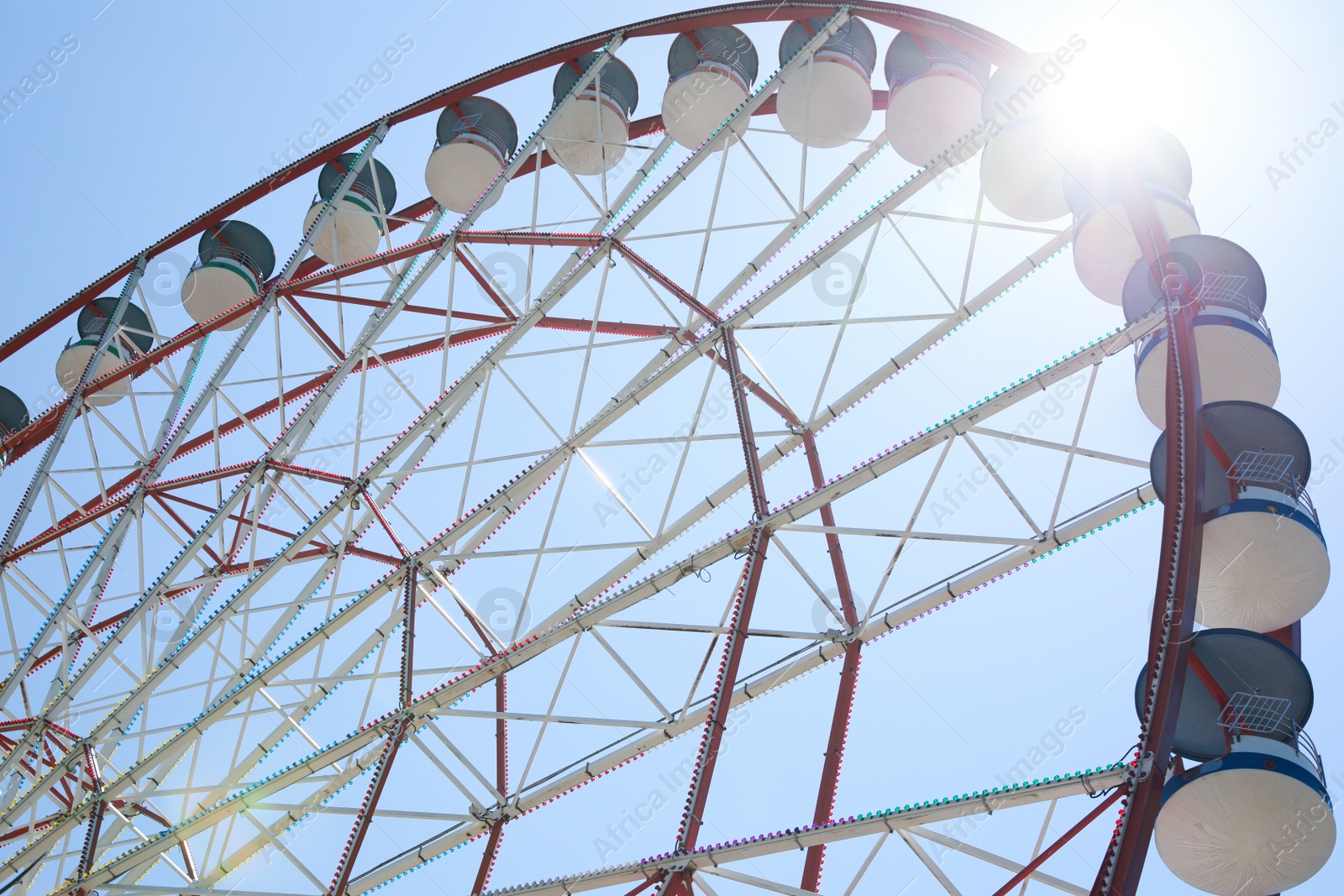 Photo of Beautiful Ferris wheel against blue sky on sunny day, low angle view