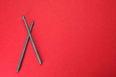Photo of Two gray drum sticks on red background, top view. Space for text