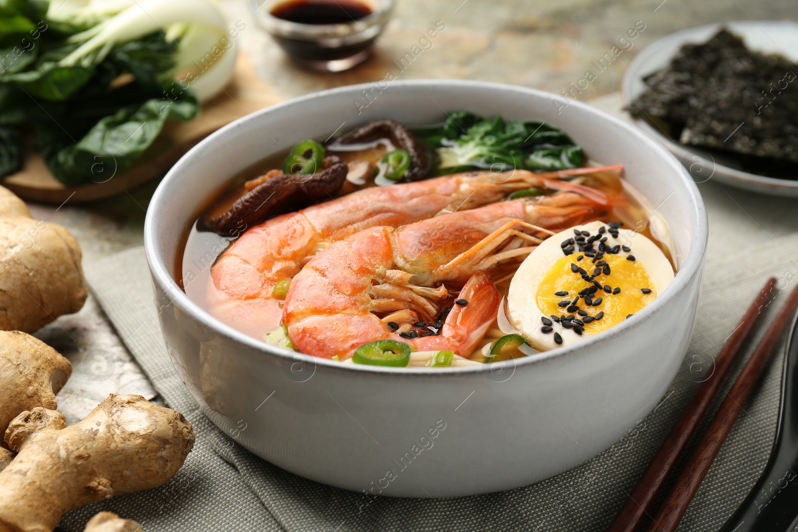 Photo of Delicious ramen with shrimps and egg in bowl served on table, closeup. Noodle soup