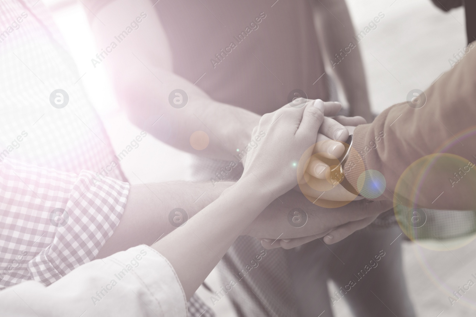 Image of Group of people holding hands together outdoors, closeup. Black and white effect